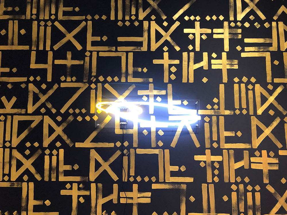 Neon circles over a mural of gold symbols on a black background