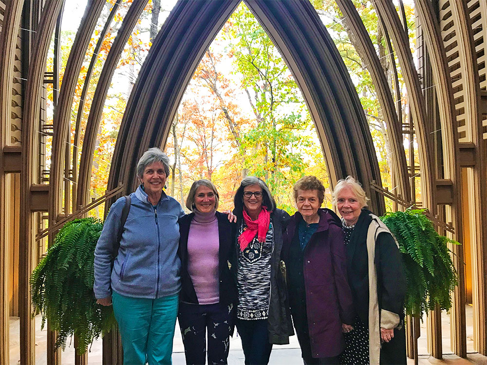 five women stand beneath a large pointed archway