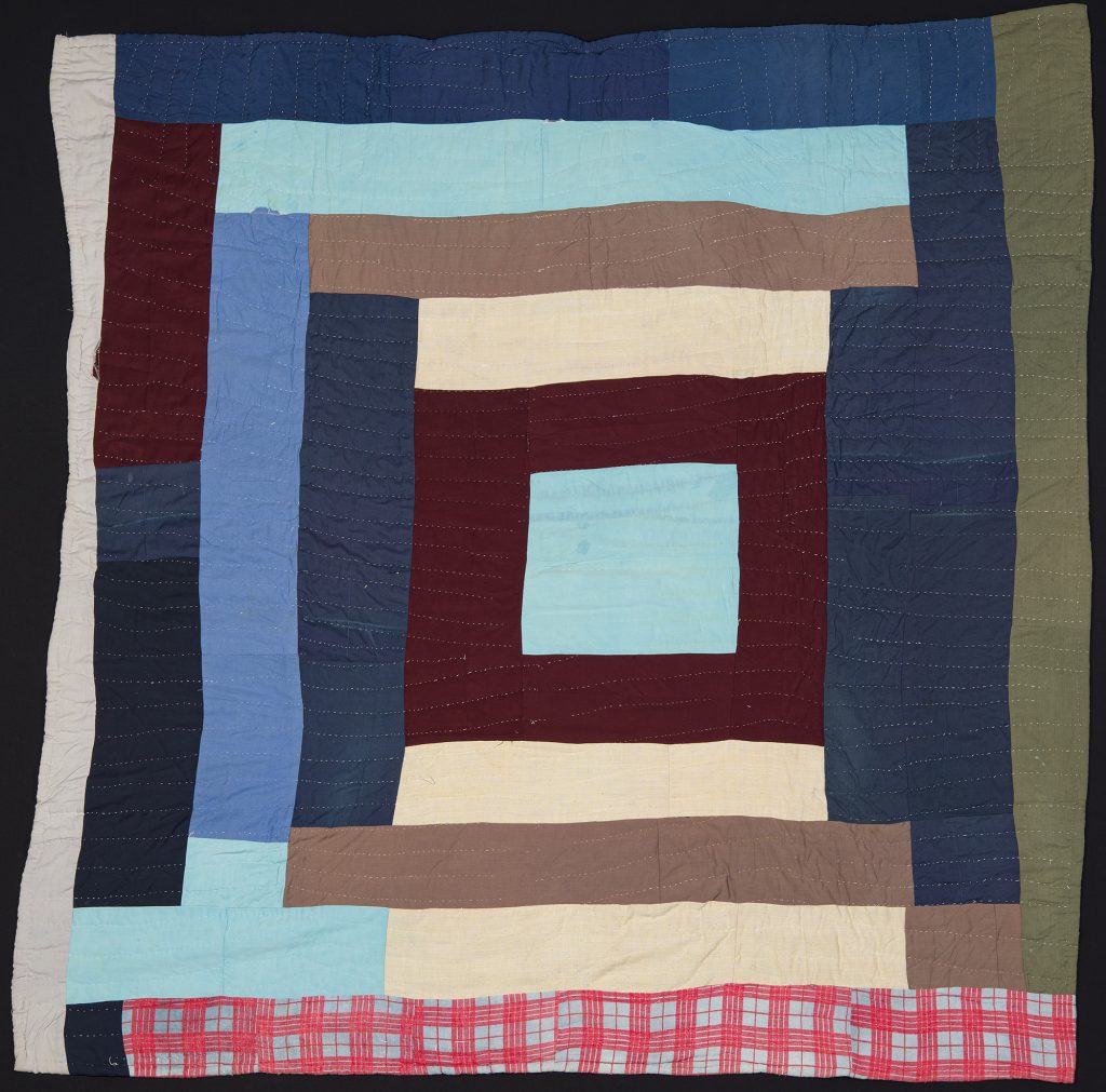 Quilt made of rectangle scrap pieces of fabric framing a central square.
