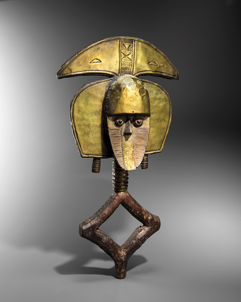 A yellow metal reliquary in the shape of a person's face and upper body