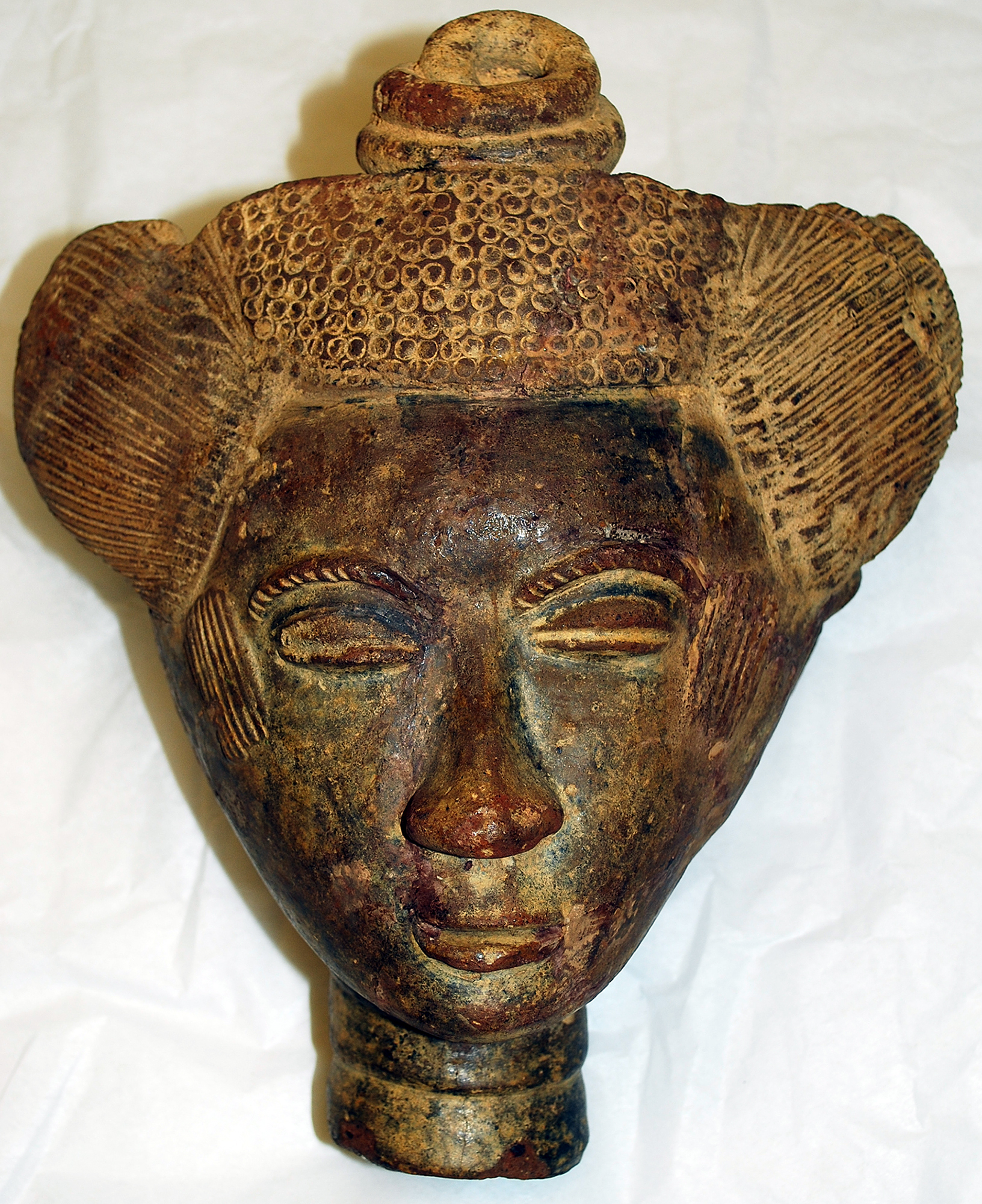 A sculpture of a human head carved from deep brown wood