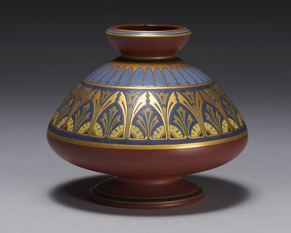 A red-brown vase decorated with blue and gold ornamental patterns