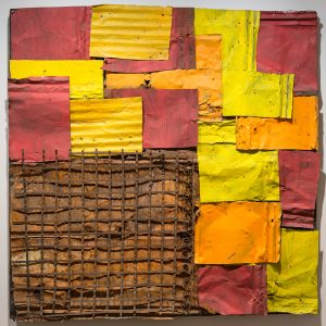 Square mixed-media artwork made of red, orange, and yellow patches of metal with rusted metal in the bottom left corner.