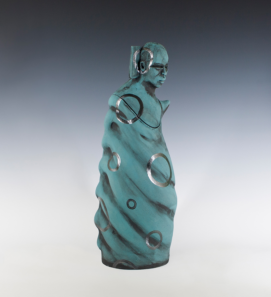 A blue-green sculpture of a human figure swathed in fabric with large silver circles